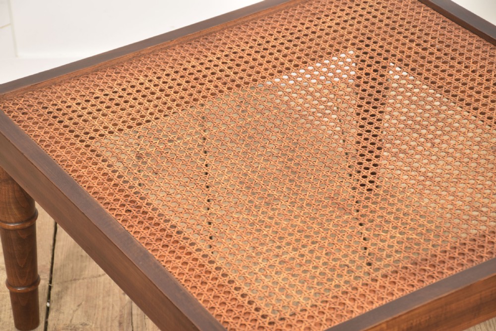 A square mahogany coffee table featuring a woven cane top set within a solid wood frame and supported by turned legs. View V