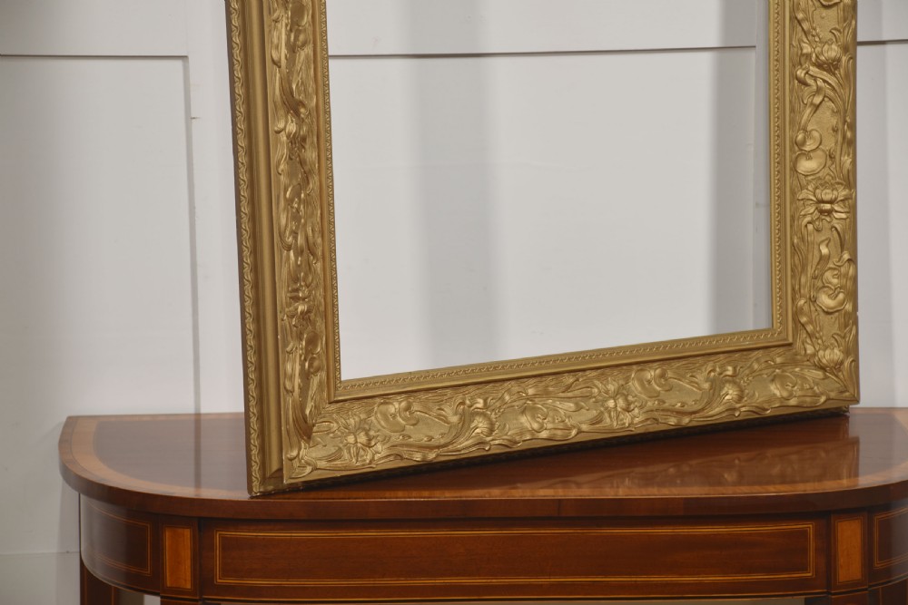 A large rectangular giltwood picture frame featuring deep-relief Art Nouveau floral and botanical carvings along the profile. View V