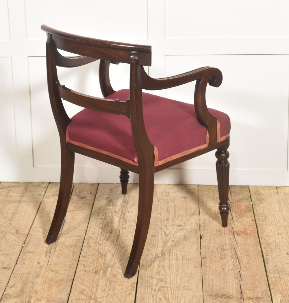 A pair of George IV mahogany armchairs featuring carved curved crest rails, swept arm supports, reeded front legs, and red fabric seats. View II