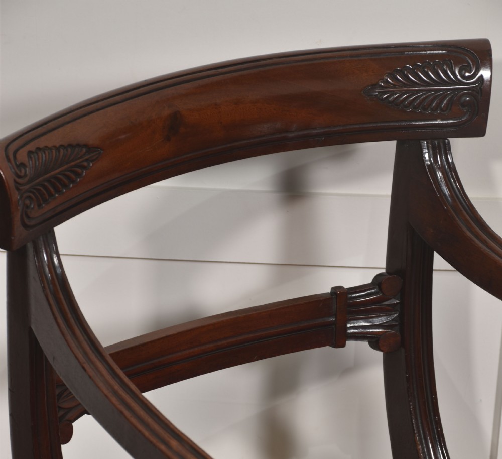A pair of George IV mahogany armchairs featuring carved curved crest rails, swept arm supports, reeded front legs, and red fabric seats. View VI