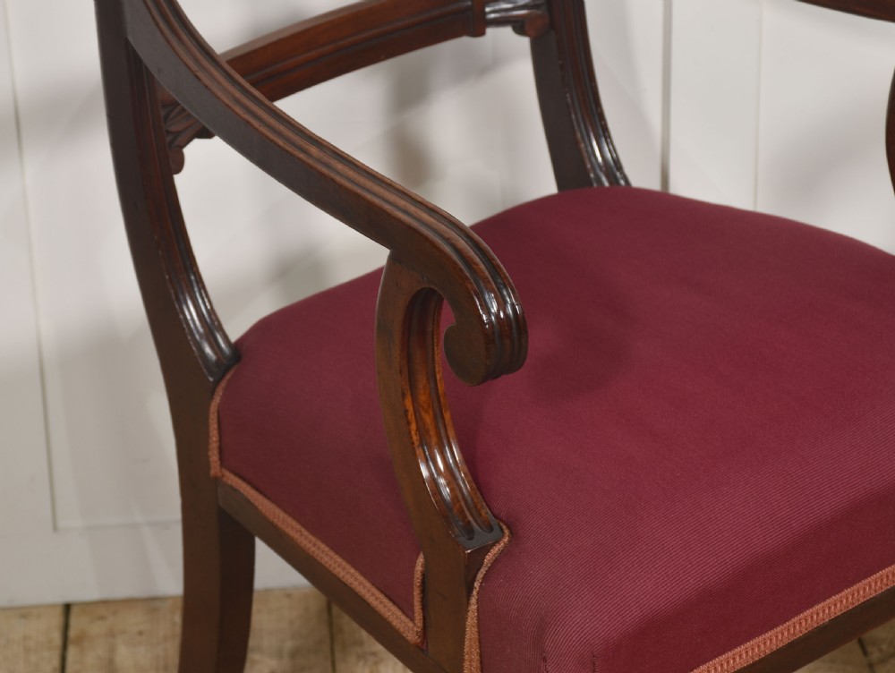 A pair of George IV mahogany armchairs featuring carved curved crest rails, swept arm supports, reeded front legs, and red fabric seats. View VII