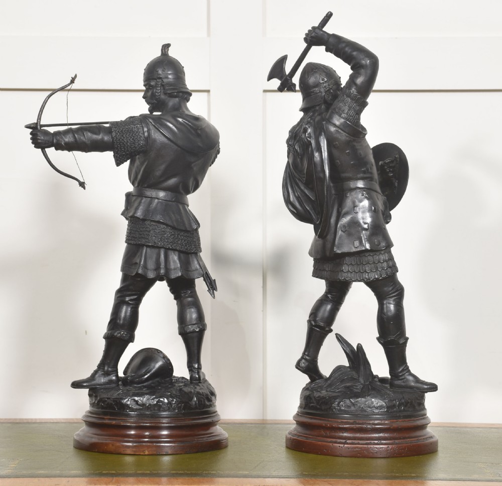 A pair of dark bronzed metal figures depicting Anglo-Saxon warriors, one drawn with a bow and the other raising an axe, mounted on circular wooden bases. View VIII