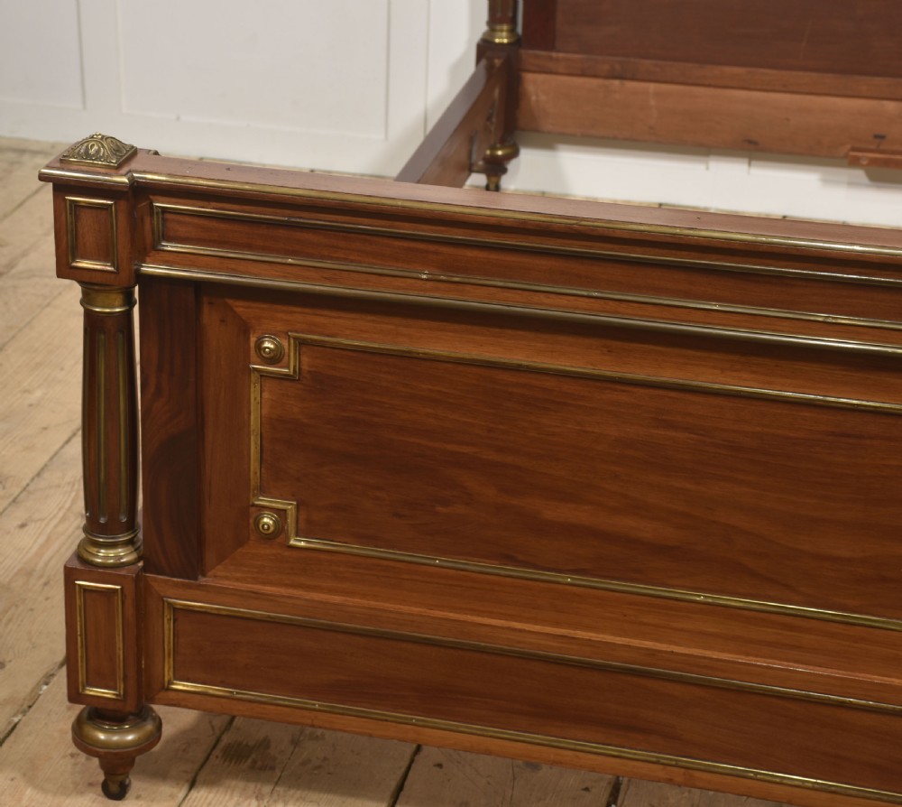 Late nineteenth-century mahogany bedframe featuring brass mouldings, fluted post columns topped with pineapple finials, and raised panel work on the headboard and footboard. View VI