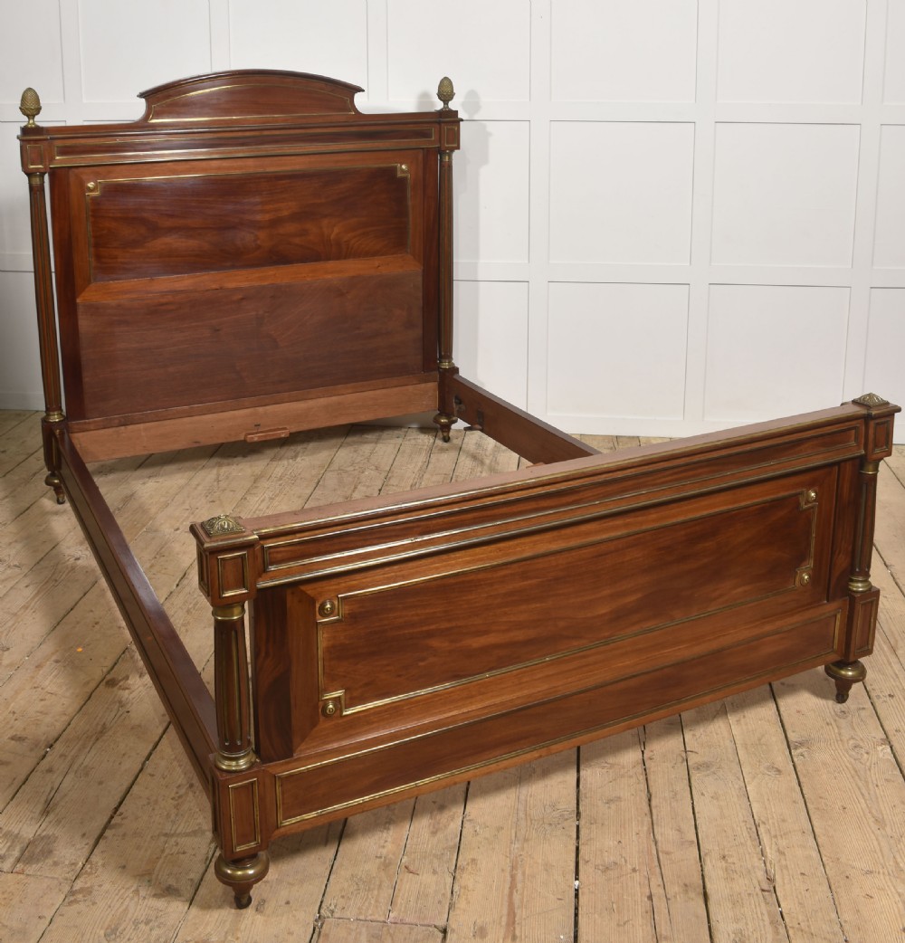 Late nineteenth-century mahogany bedframe featuring brass mouldings, fluted post columns topped with pineapple finials, and raised panel work on the headboard and footboard. View VII