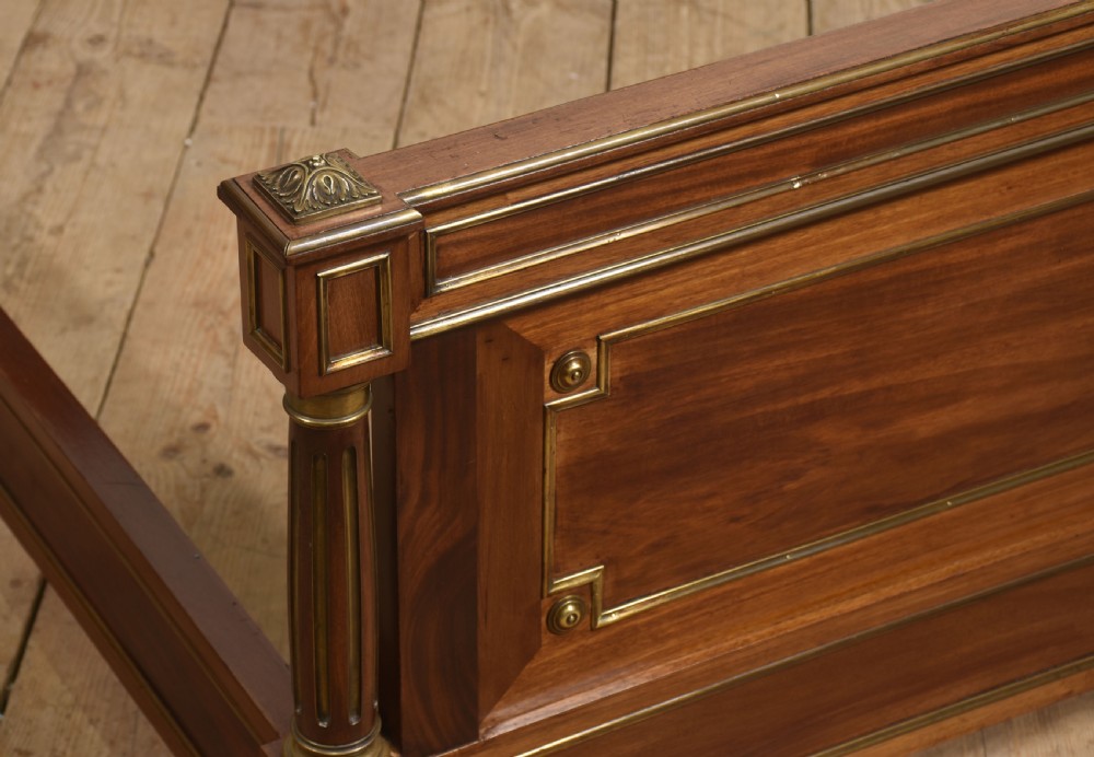 Late nineteenth-century mahogany bedframe featuring brass mouldings, fluted post columns topped with pineapple finials, and raised panel work on the headboard and footboard. View IX