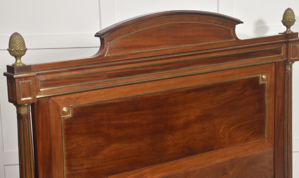 Late nineteenth-century mahogany bedframe featuring brass mouldings, fluted post columns topped with pineapple finials, and raised panel work on the headboard and footboard. View XII