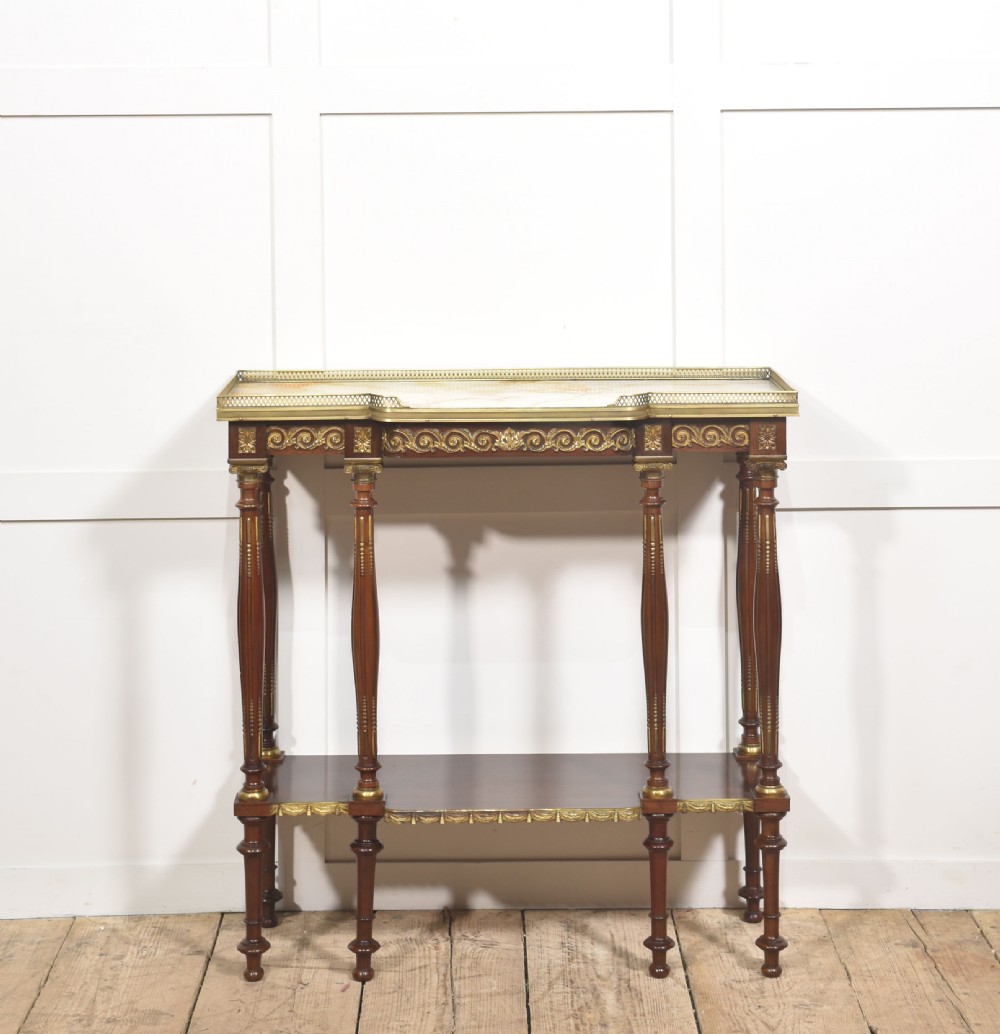Regency Revival mahogany console table featuring a marble top with a brass gallery, gilt mounts, turned fluted legs, and a lower tier shelf.