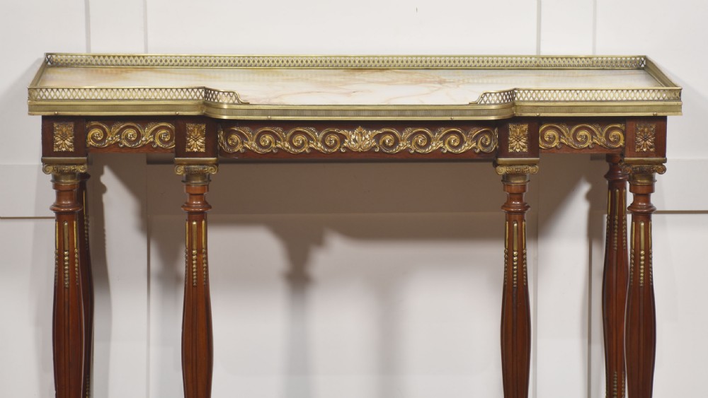 Regency Revival mahogany console table featuring a marble top with a brass gallery, gilt mounts, turned fluted legs, and a lower tier shelf. View II