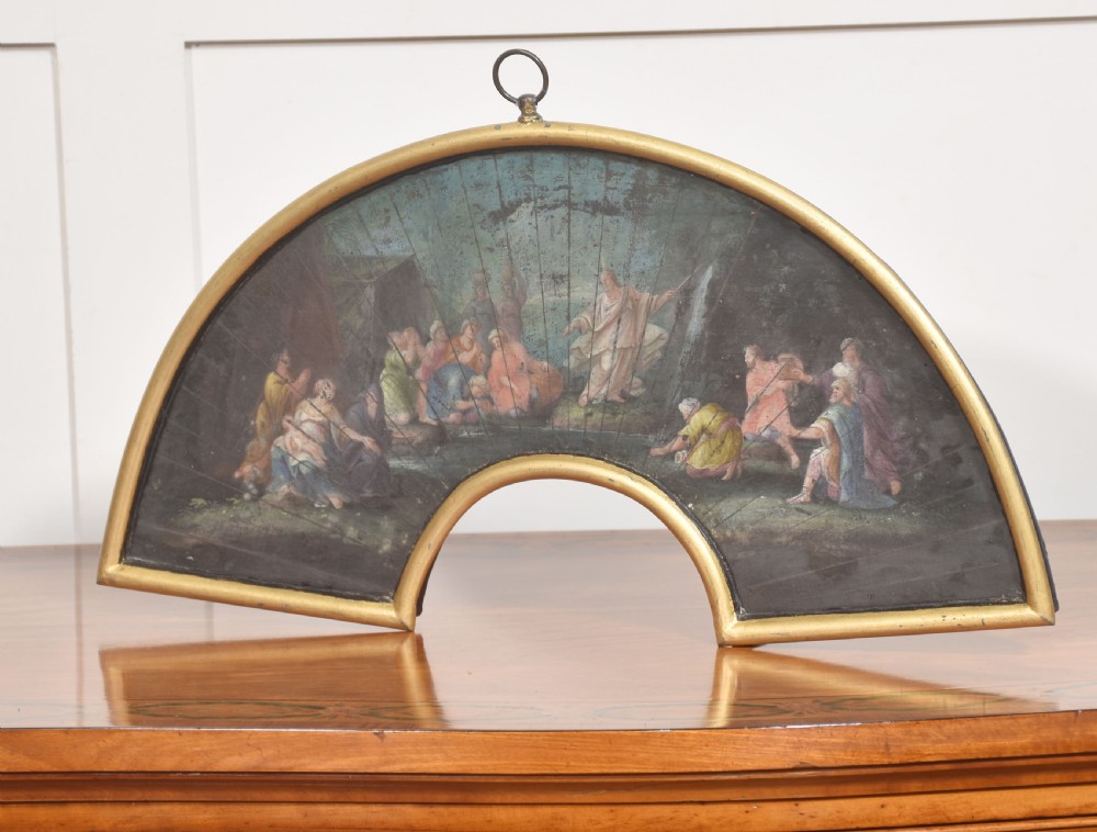 A fan-shaped gilt metal frame containing a hand-painted antique fan leaf depicting a biblical scene with figures in classical drapery. View V