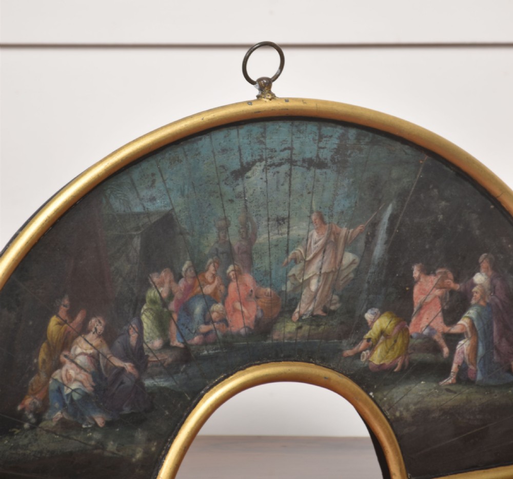 A fan-shaped gilt metal frame containing a hand-painted antique fan leaf depicting a biblical scene with figures in classical drapery. View VI