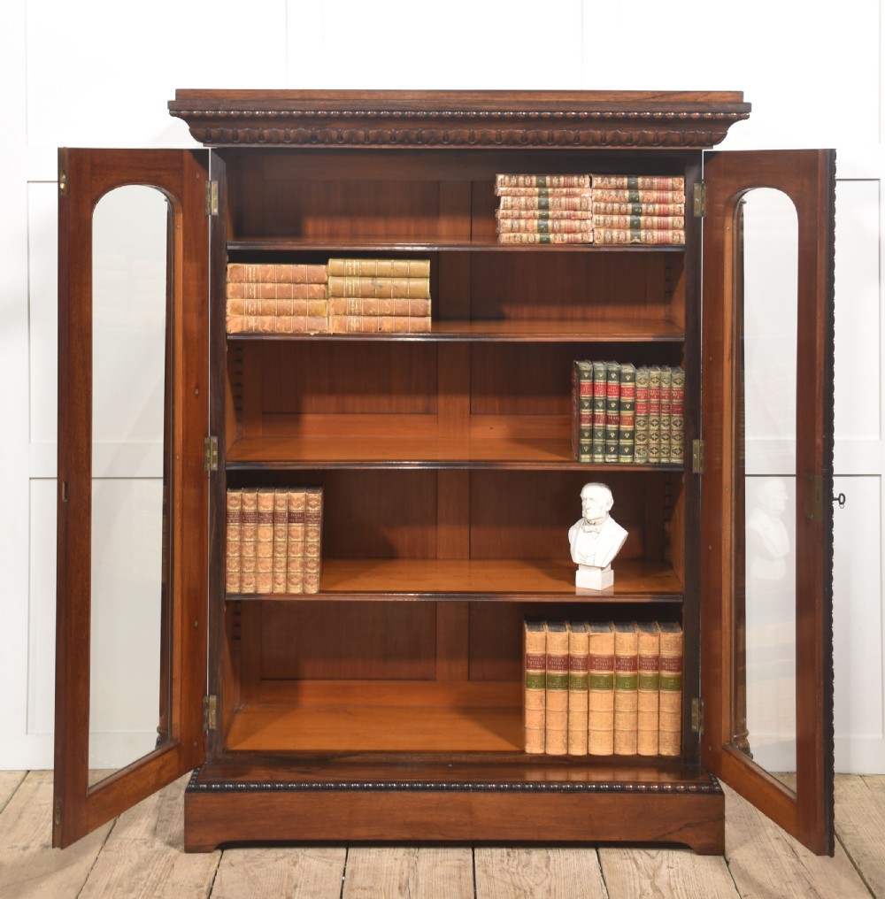 A 19th-century dark rosewood glazed low bookcase featuring two arched glass doors, fluted side pilasters, and carved mouldings. View VII