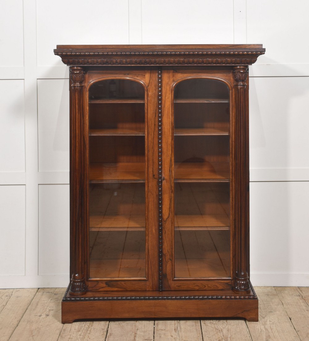 A 19th-century dark rosewood glazed low bookcase featuring two arched glass doors, fluted side pilasters, and carved mouldings. View XIV