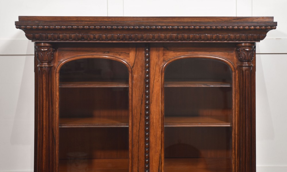 A 19th-century dark rosewood glazed low bookcase featuring two arched glass doors, fluted side pilasters, and carved mouldings. View XV