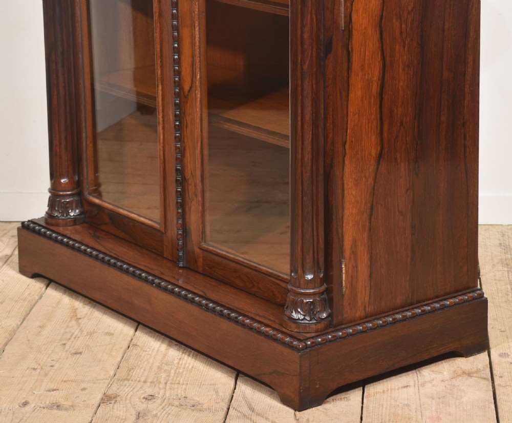 A 19th-century dark rosewood glazed low bookcase featuring two arched glass doors, fluted side pilasters, and carved mouldings. View XIX