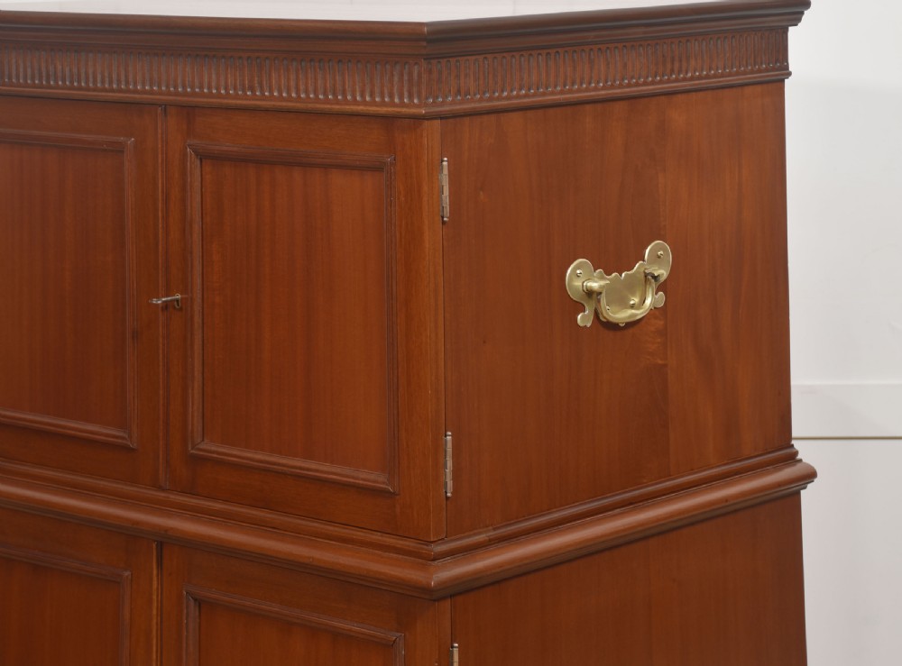 A two-section mahogany collectors cabinet featuring double doors that open to reveal stacked drawers with flush brass handles. View V