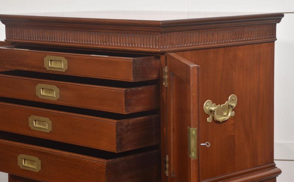 A two-section mahogany collectors cabinet featuring double doors that open to reveal stacked drawers with flush brass handles. View VII