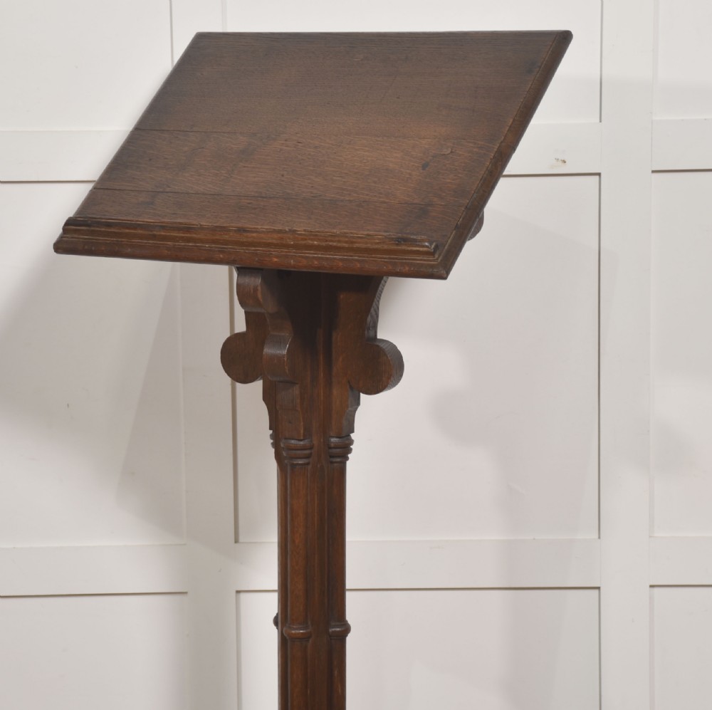 A dark carved oak Gothic Revival lectern stand featuring a sloped top, trefoil cut-outs, a central column, and a four-legged base. View IX