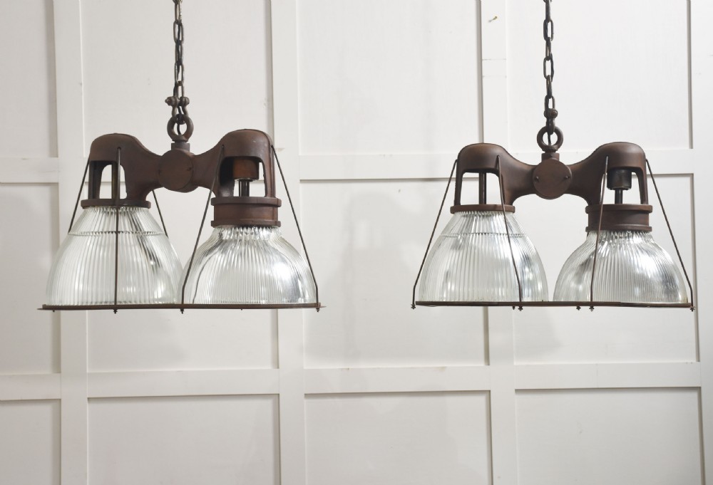 A pair of double-dome industrial pendant lights featuring clear ribbed Holophane glass shades set in dark brown metal frames with chain supports.