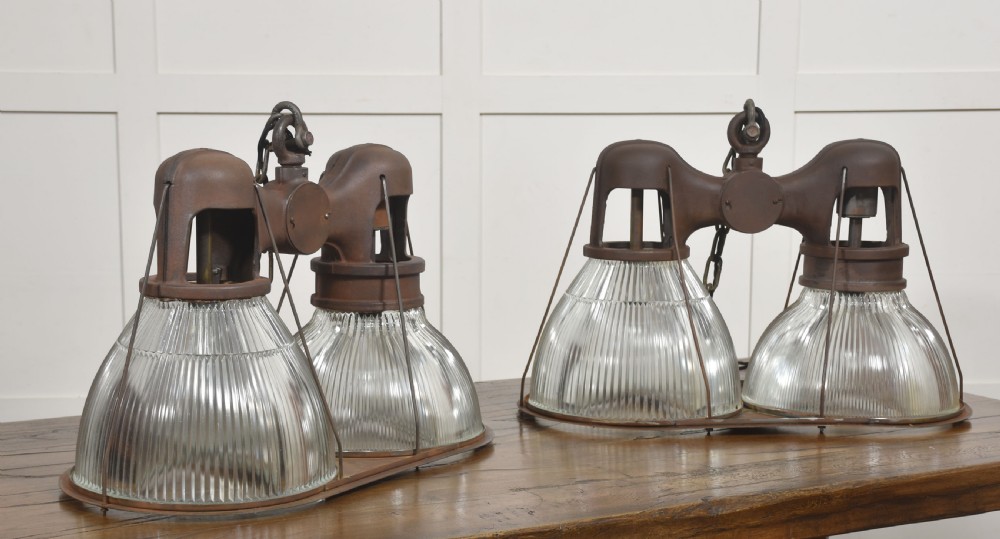 A pair of double-dome industrial pendant lights featuring clear ribbed Holophane glass shades set in dark brown metal frames with chain supports. View V