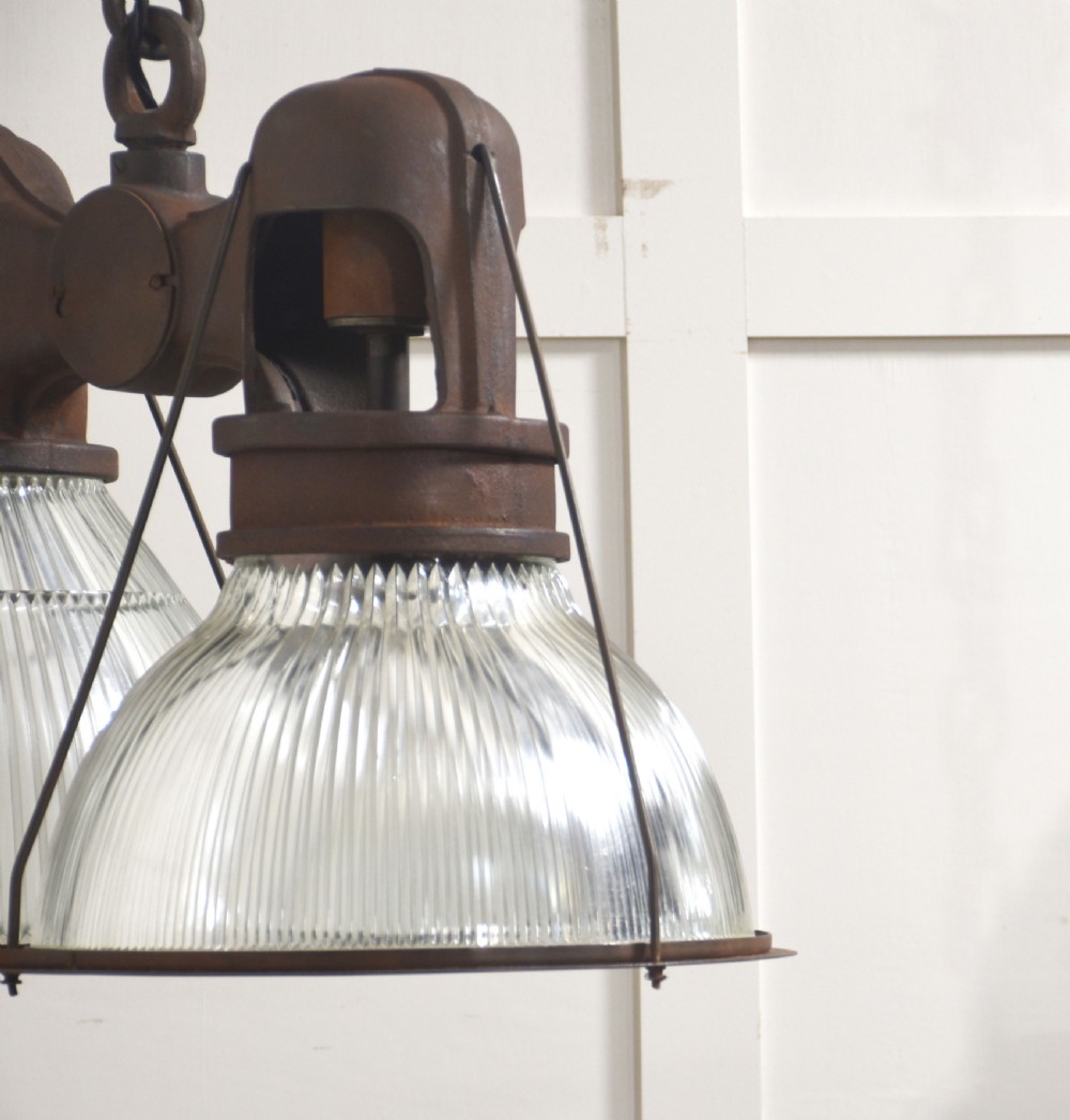 A pair of double-dome industrial pendant lights featuring clear ribbed Holophane glass shades set in dark brown metal frames with chain supports. View VII