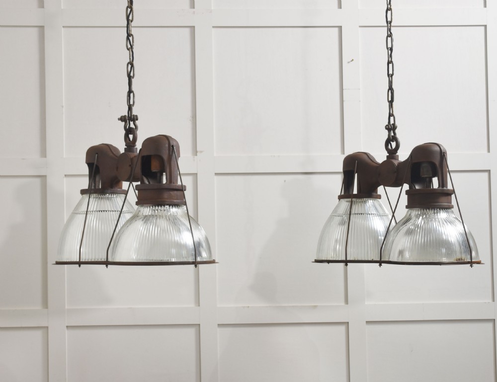 A pair of double-dome industrial pendant lights featuring clear ribbed Holophane glass shades set in dark brown metal frames with chain supports. View VIII