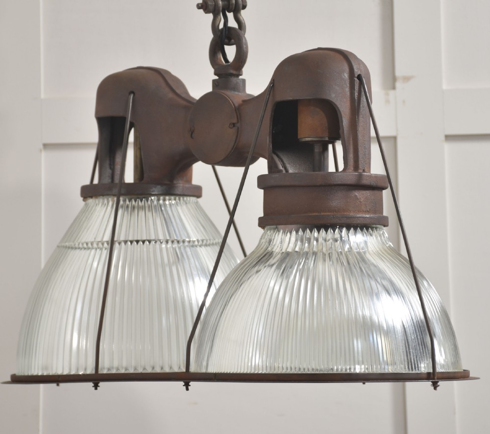 A pair of double-dome industrial pendant lights featuring clear ribbed Holophane glass shades set in dark brown metal frames with chain supports. View X