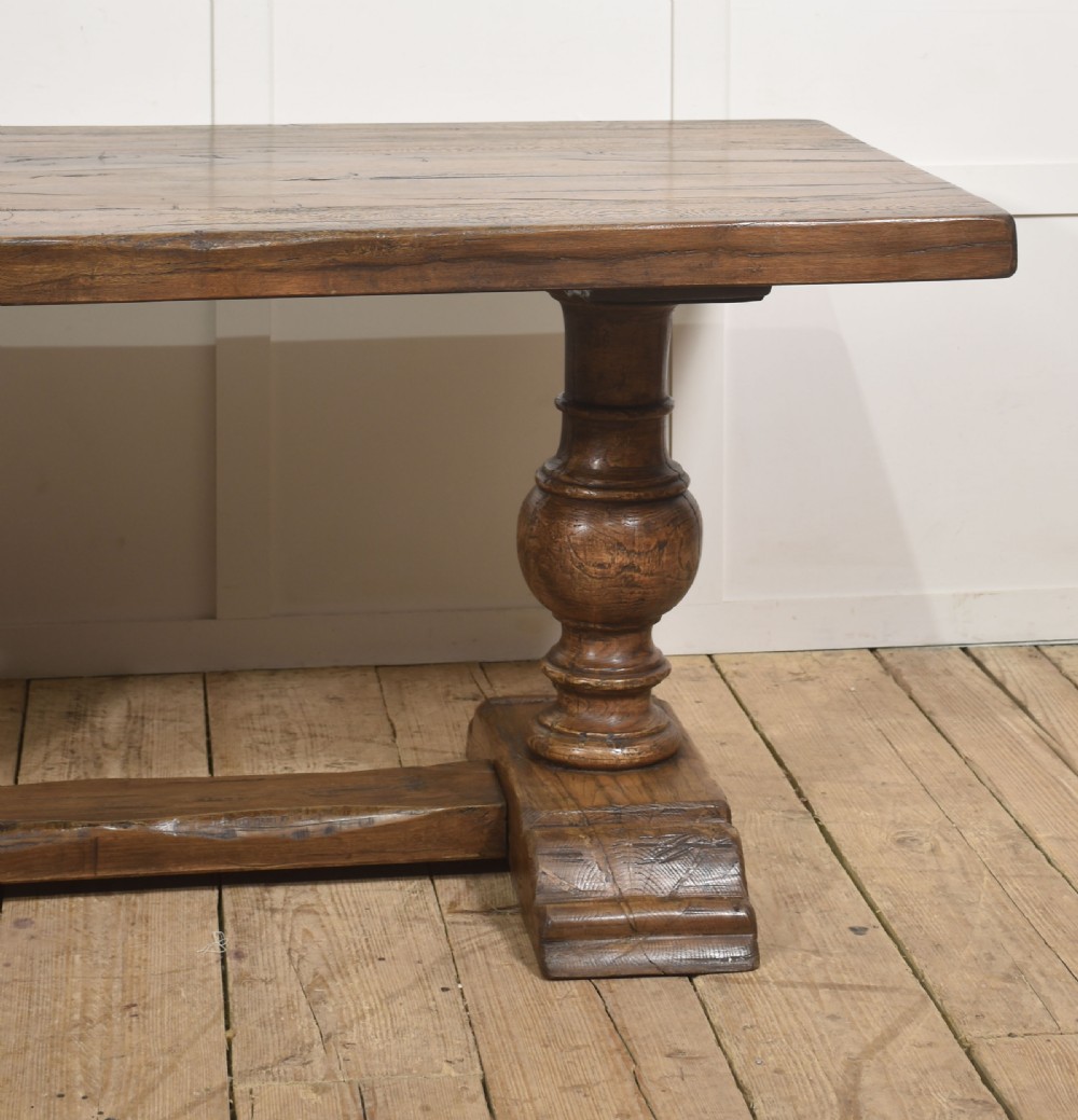 Solid oak refectory dining table featuring thick timber top, bulbous turned baluster pedestals, and a floor stretcher rail. View III