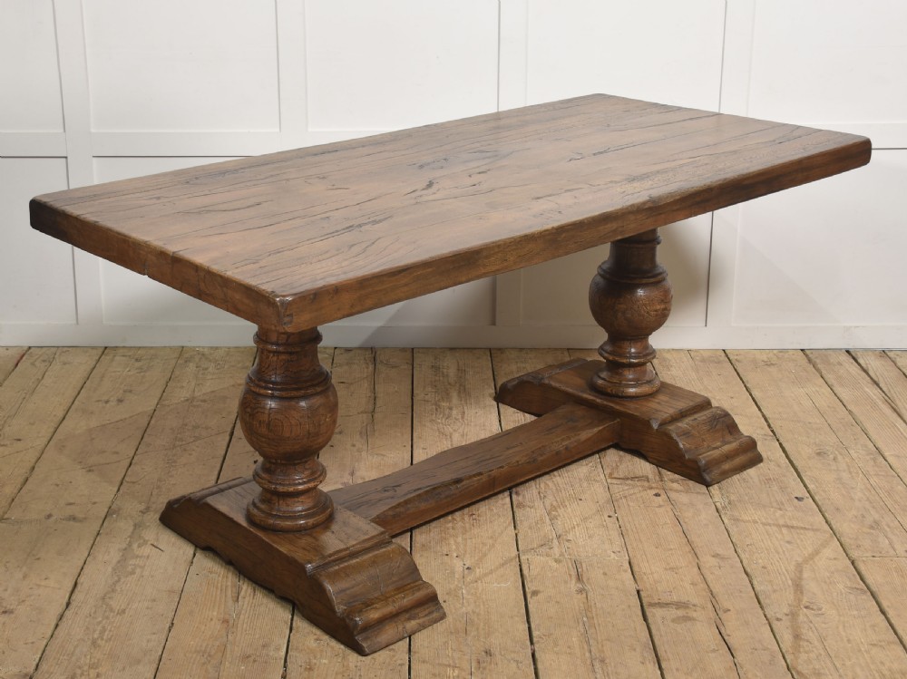 Solid oak refectory dining table featuring thick timber top, bulbous turned baluster pedestals, and a floor stretcher rail. View VII