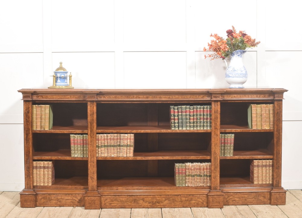 A low three-section breakfront open bookcase made from burr walnut veneer with adjustable shelves and a plinth base. View II