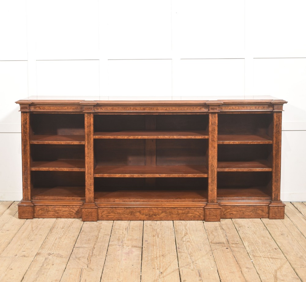 A low three-section breakfront open bookcase made from burr walnut veneer with adjustable shelves and a plinth base. View XV