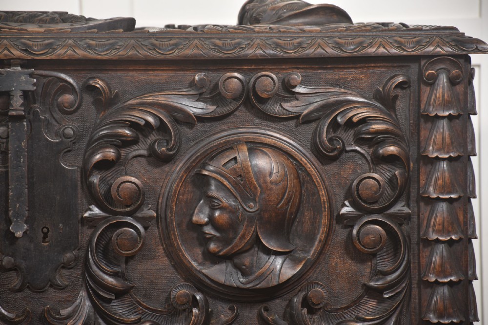 A dark carved walnut coffer featuring two profile portrait medallions surrounded by intricate acanthus foliage carving and a central iron lock plate. View II