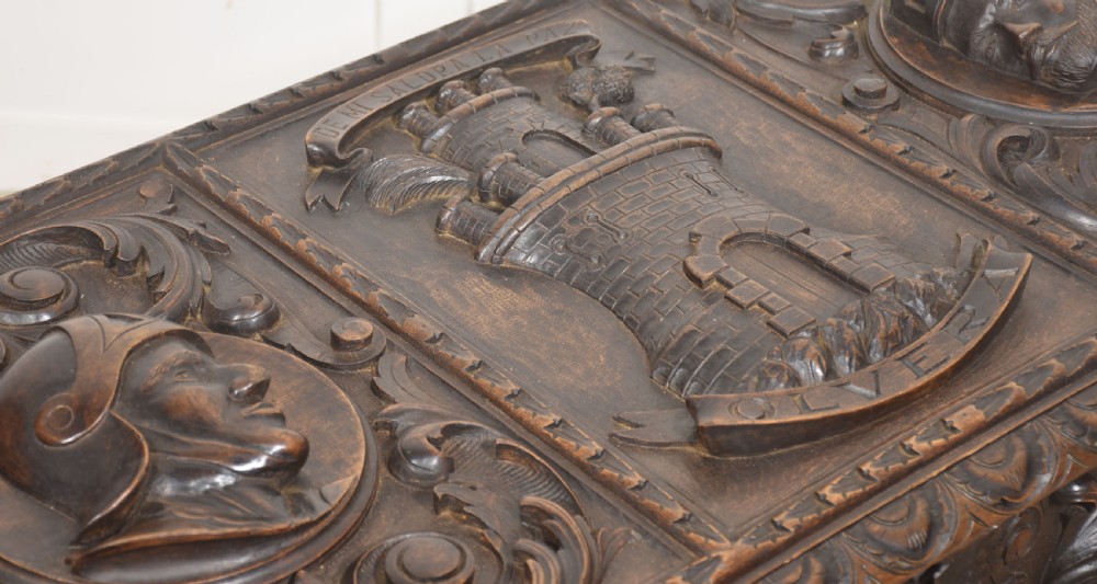 A dark carved walnut coffer featuring two profile portrait medallions surrounded by intricate acanthus foliage carving and a central iron lock plate. View VII