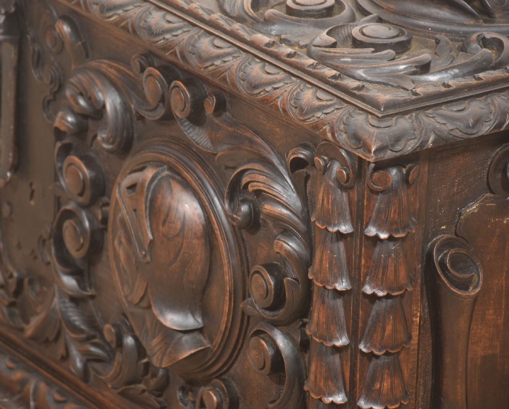 A dark carved walnut coffer featuring two profile portrait medallions surrounded by intricate acanthus foliage carving and a central iron lock plate. View XIV