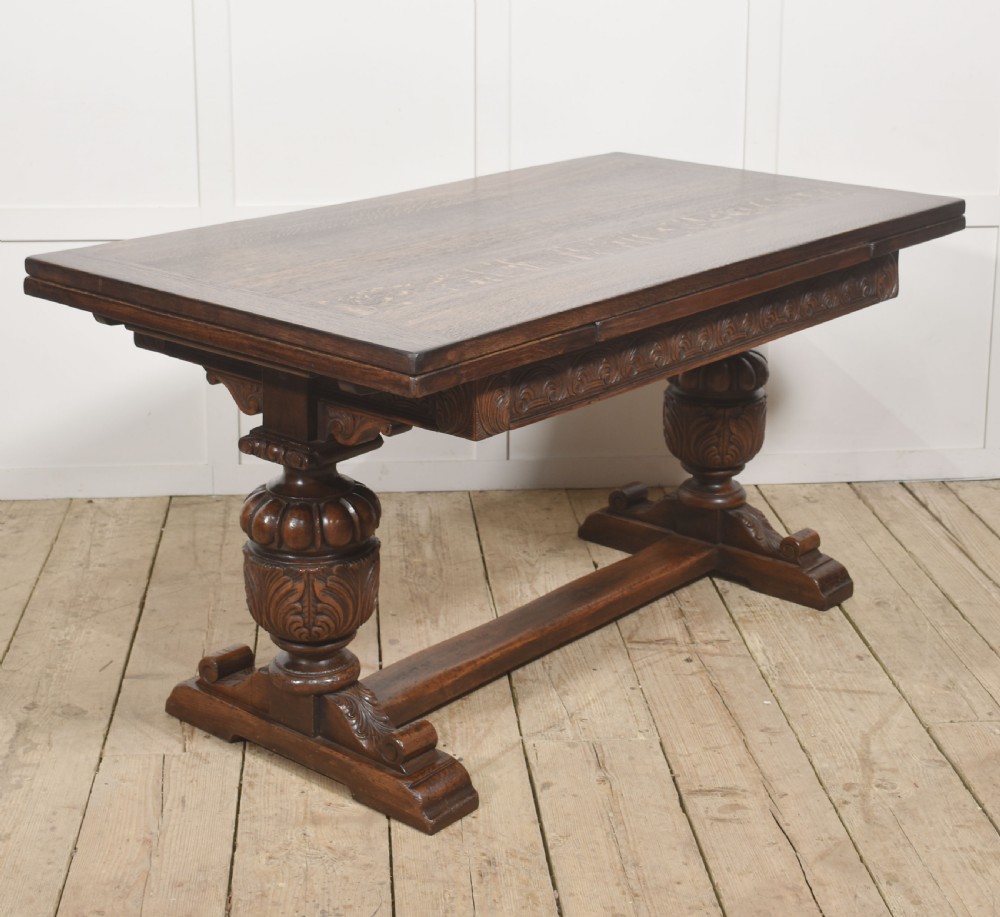 A dark carved oak refectory dining table featuring bulbous turned legs, a carved apron, and pull-out draw-leaf extensions. View IV