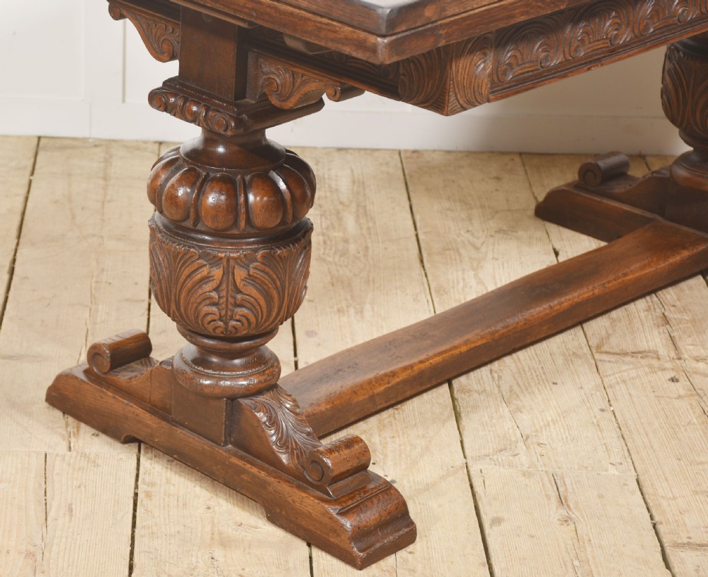 A dark carved oak refectory dining table featuring bulbous turned legs, a carved apron, and pull-out draw-leaf extensions. View V