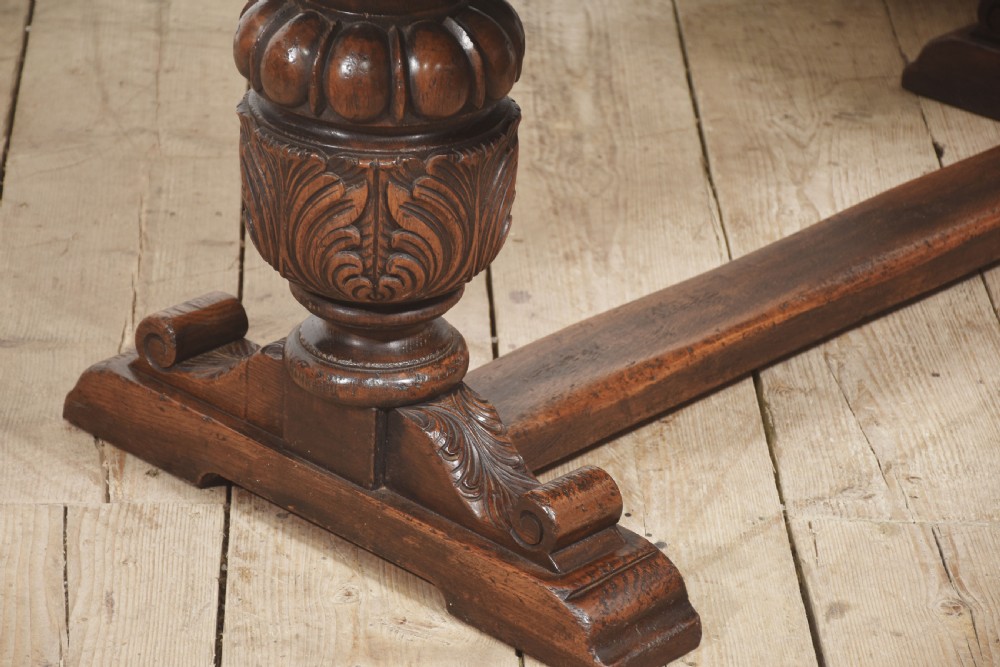 A dark carved oak refectory dining table featuring bulbous turned legs, a carved apron, and pull-out draw-leaf extensions. View VI