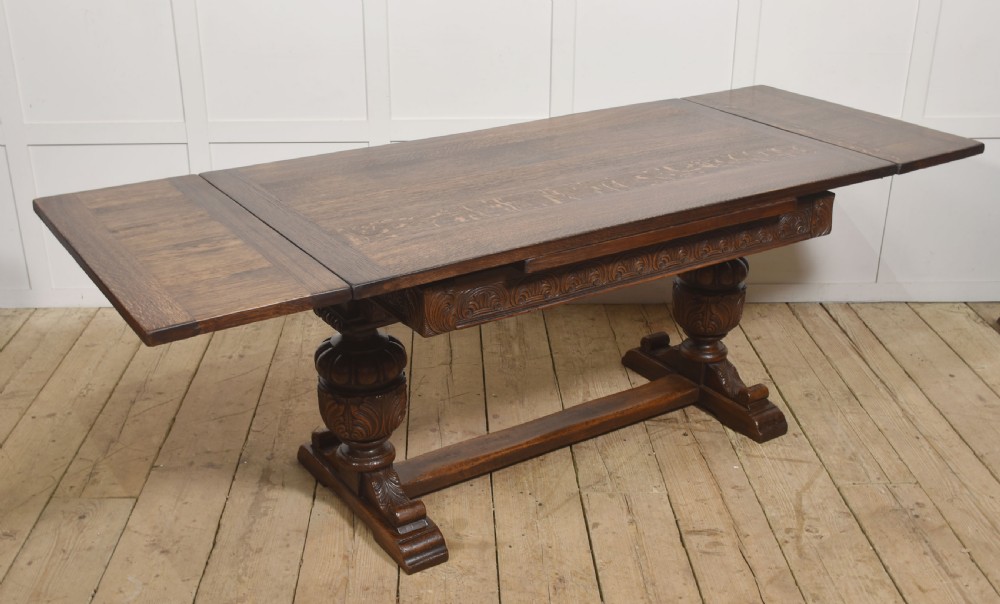 A dark carved oak refectory dining table featuring bulbous turned legs, a carved apron, and pull-out draw-leaf extensions. View VIII
