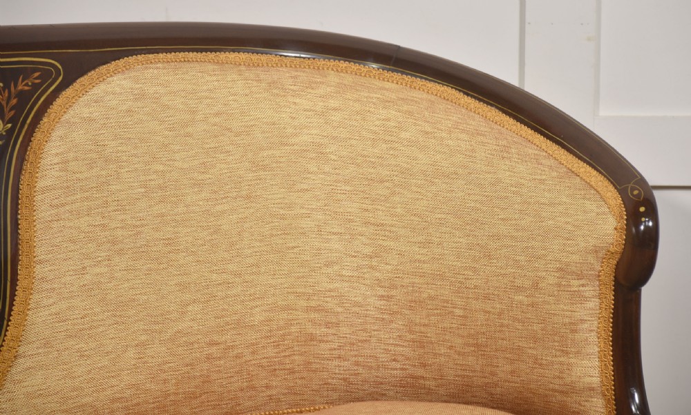 A matching pair of Edwardian mahogany settees featuring curved backs, floral marquetry central splats, and pale mustard yellow upholstered seats. View VI