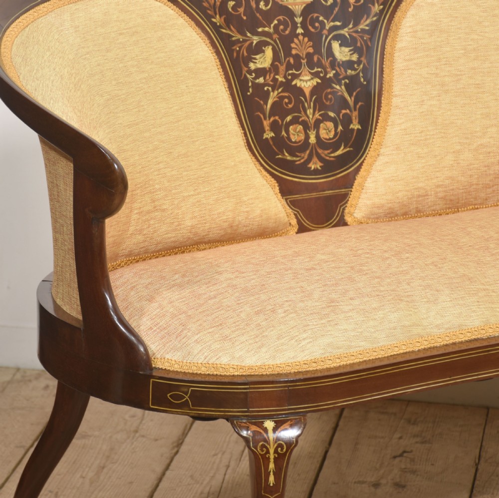 A matching pair of Edwardian mahogany settees featuring curved backs, floral marquetry central splats, and pale mustard yellow upholstered seats. View VII