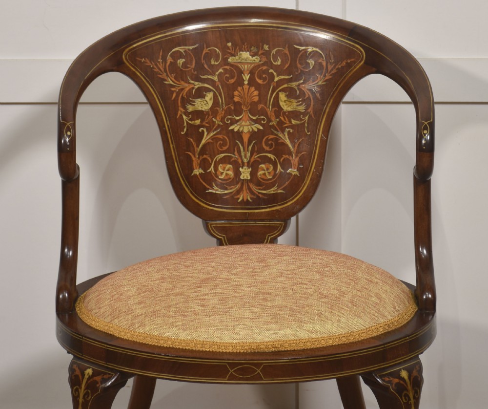 An Edwardian mahogany tub armchair displaying foliate marquetry inlay across the curved back splat and cabriole legs, paired with a textured cream seat. View VII