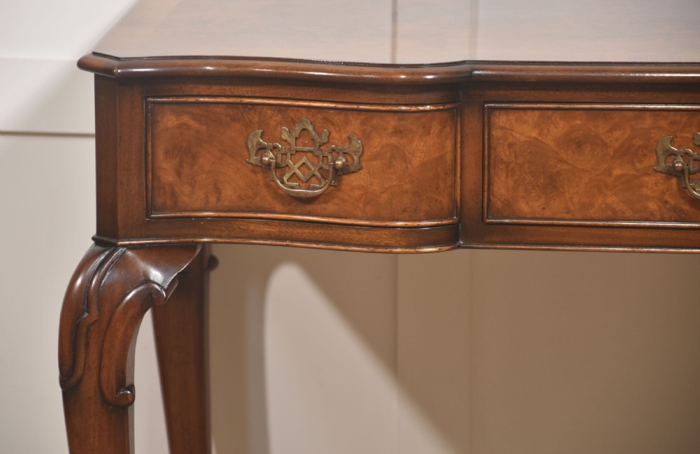 A burr walnut writing table featuring three drawers with brass handles and slender cabriole legs. View VI