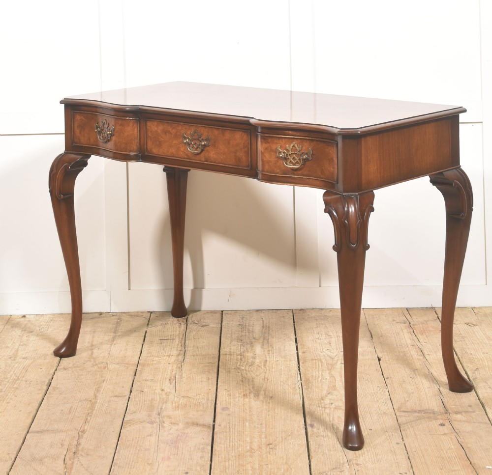 A burr walnut writing table featuring three drawers with brass handles and slender cabriole legs. View VII