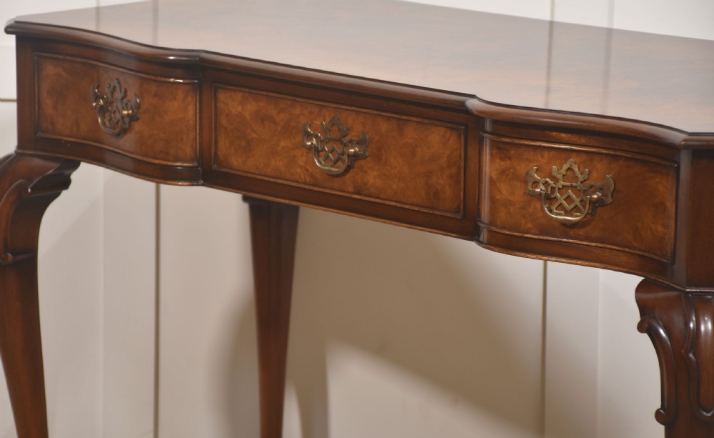 A burr walnut writing table featuring three drawers with brass handles and slender cabriole legs. View VIII