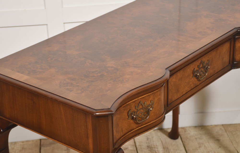 A burr walnut writing table featuring three drawers with brass handles and slender cabriole legs. View XII
