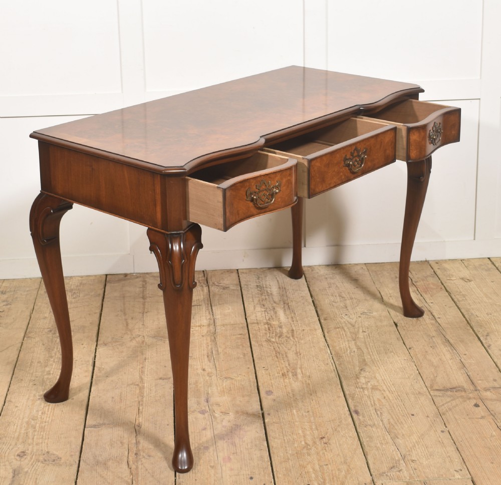 A burr walnut writing table featuring three drawers with brass handles and slender cabriole legs. View XIII