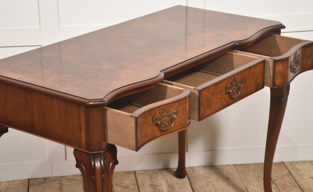 A burr walnut writing table featuring three drawers with brass handles and slender cabriole legs. View XIV