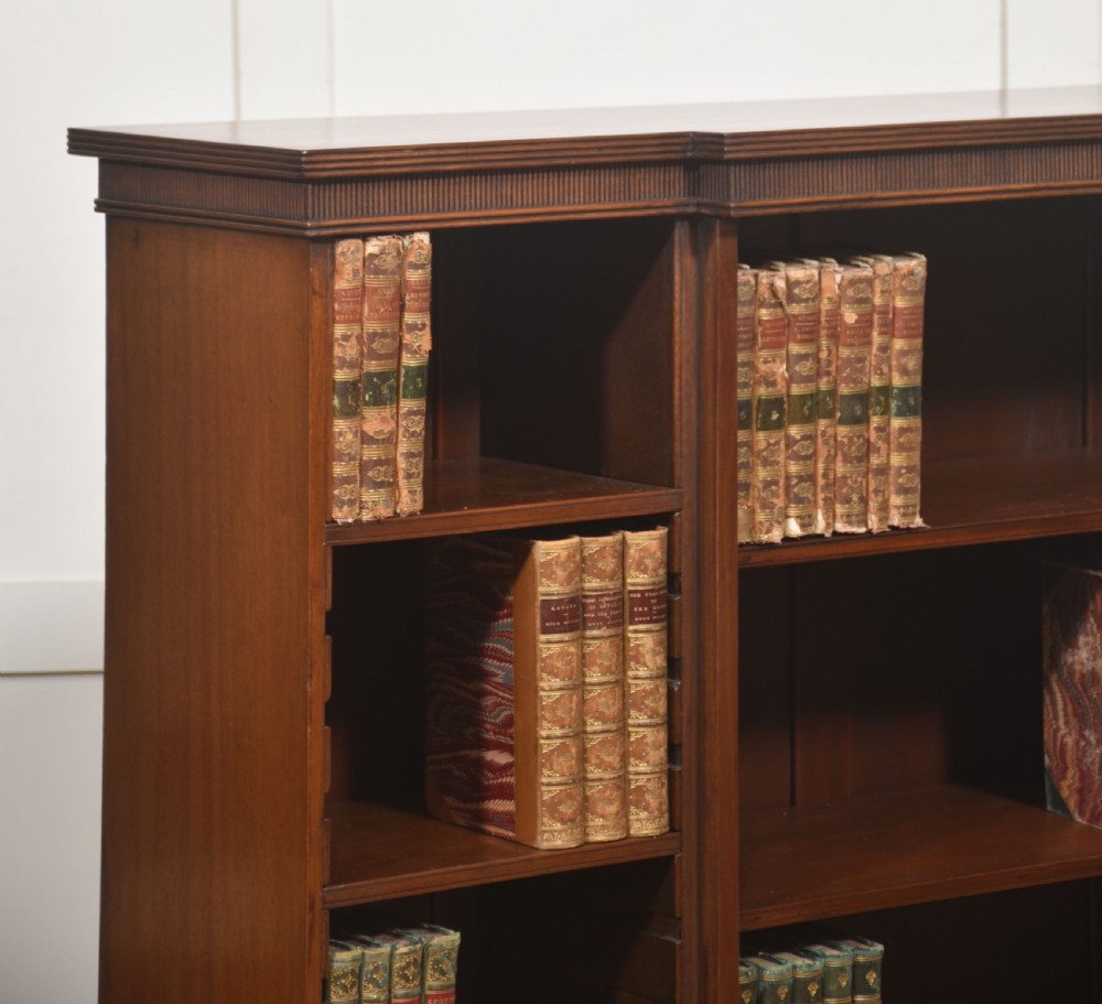 A low mahogany breakfront open bookcase featuring a reeded frieze top, adjustable shelf sections, and bracket feet. View V