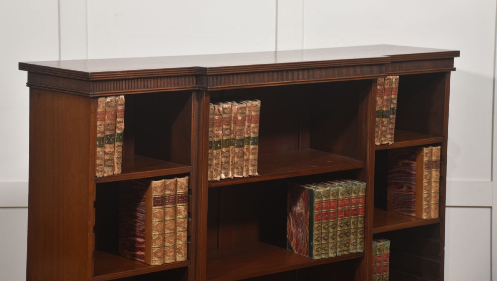 A low mahogany breakfront open bookcase featuring a reeded frieze top, adjustable shelf sections, and bracket feet. View VI