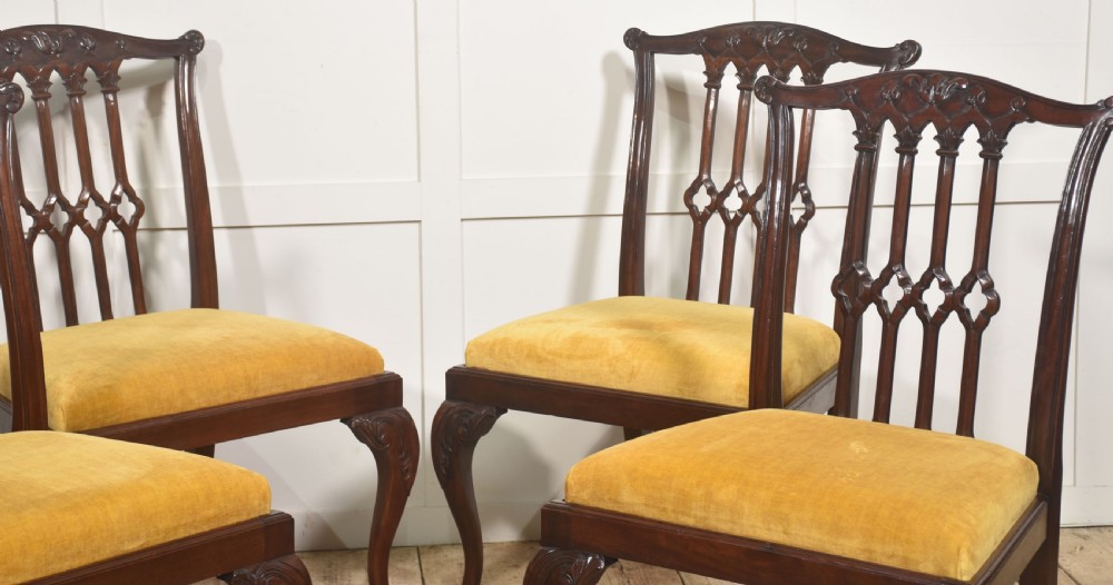 Set of four dark mahogany dining chairs featuring carved pierced splats, yellow velvet upholstered seats, and cabriole front legs with ball and claw feet. View II