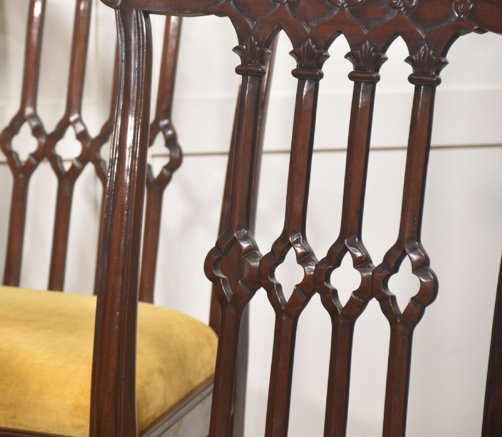 Set of four dark mahogany dining chairs featuring carved pierced splats, yellow velvet upholstered seats, and cabriole front legs with ball and claw feet. View III